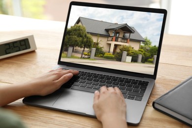 Image of Woman looking for house on real estate market website at table, closeup