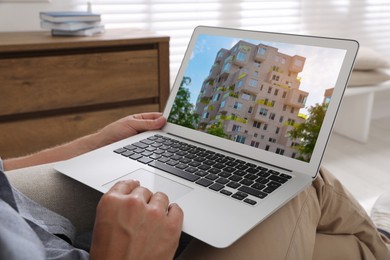 Image of Man looking for house on real estate market website at home, closeup