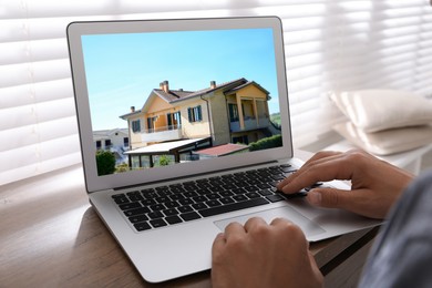 Image of Man looking for house on real estate market website at table, closeup