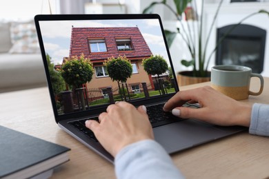 Image of Woman looking for house on real estate market website at table, closeup