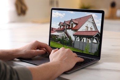 Image of Man looking for house on real estate market website at table, closeup