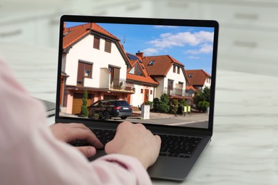 Image of Woman looking for house on real estate market website at table, closeup