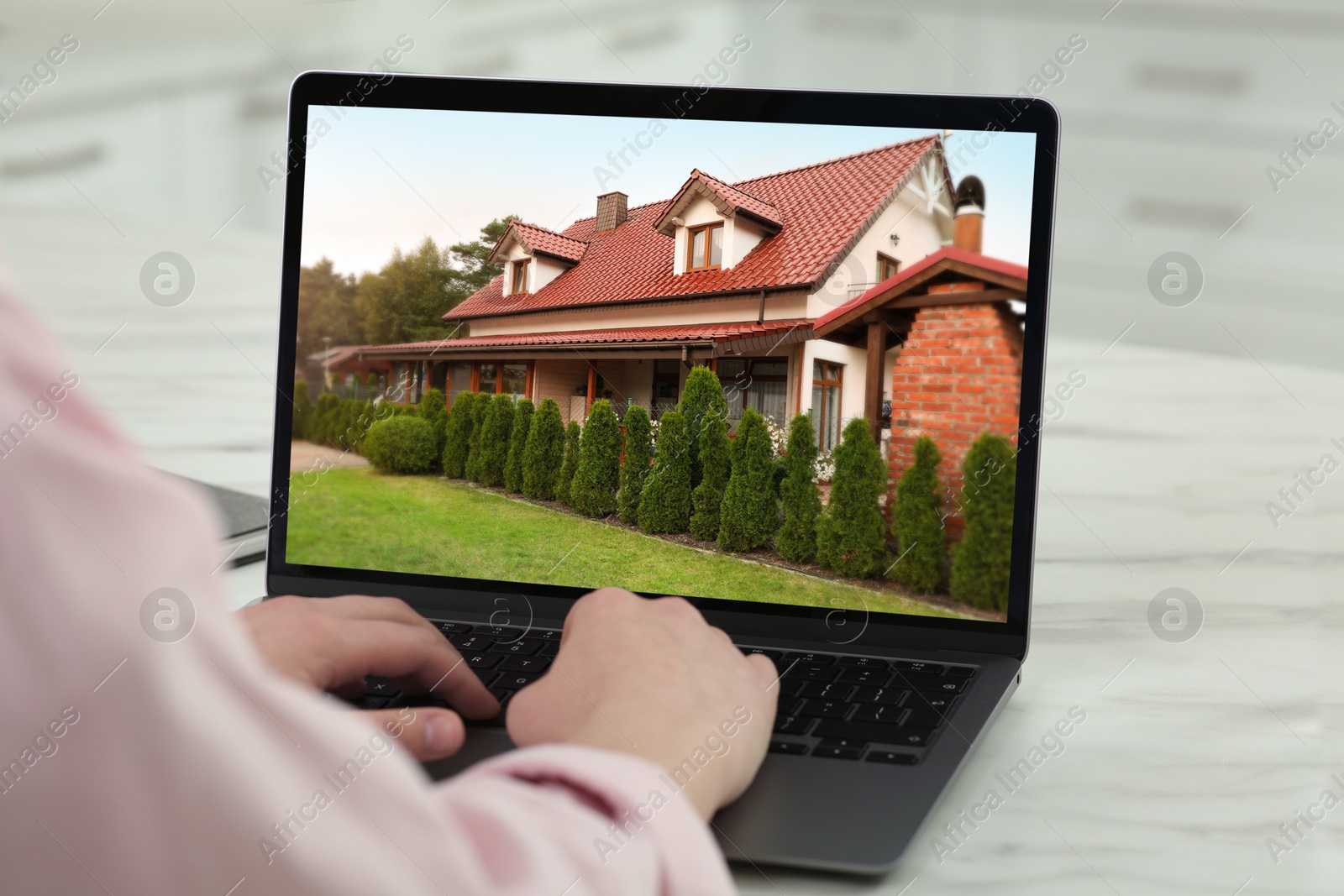 Image of Woman looking for house on real estate market website at table, closeup