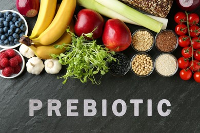 Image of Word Prebiotic and different gut-healthy foods on dark table, top view