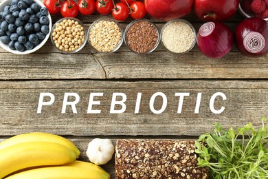 Image of Word Prebiotic and different gut-healthy foods on wooden table, top view