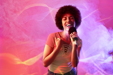 Curly young woman with microphone singing in neon lights on pink background. Audio waveforms near her