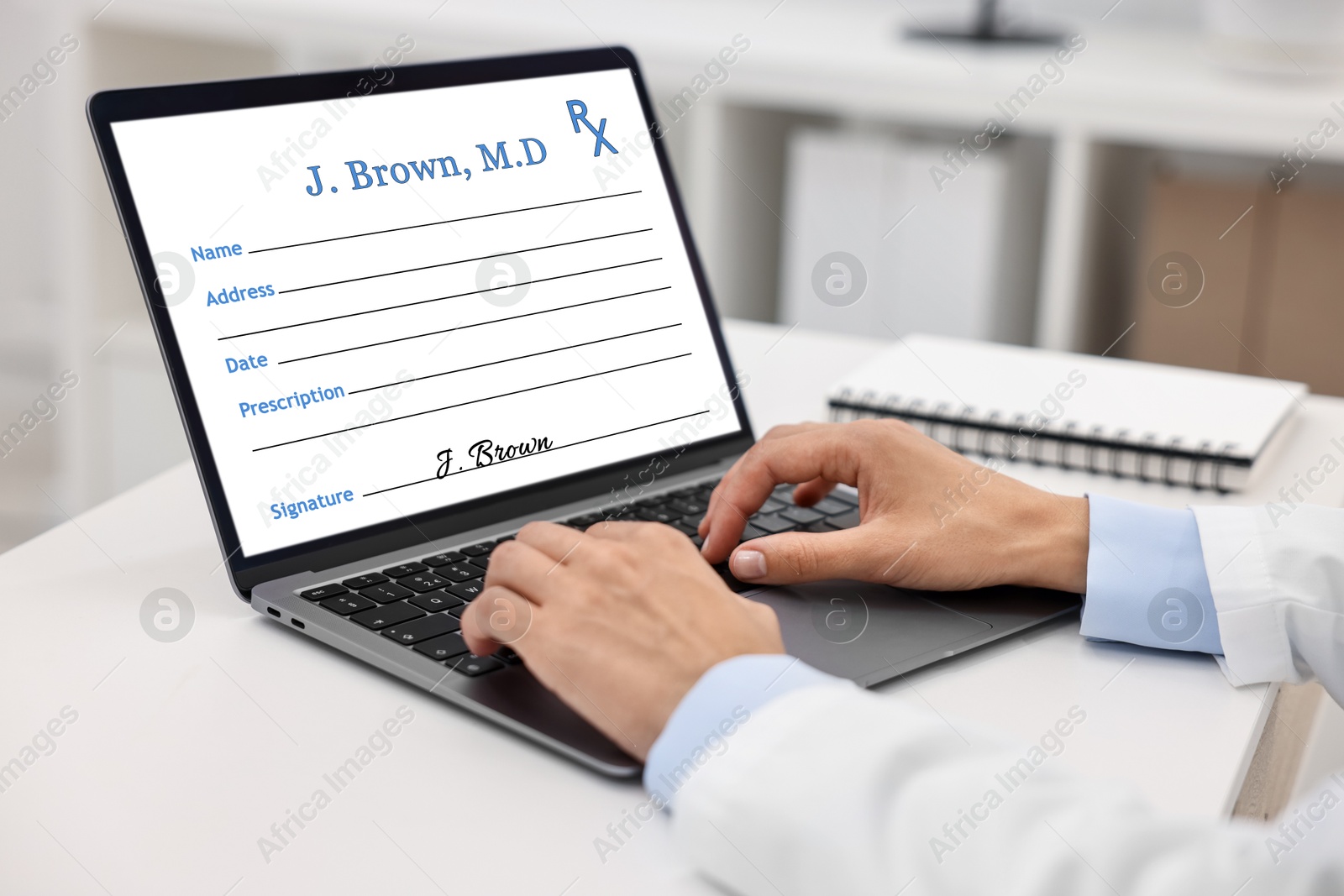 Image of Doctor filling in medical prescription on laptop at table in hospital, closeup