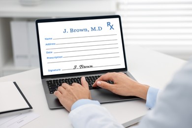 Image of Doctor filling in medical prescription on laptop at table in hospital, closeup