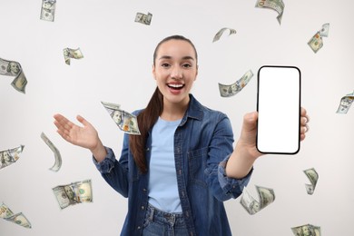 Image of Happy woman showing mobile phone with empty screen under money rain on white background