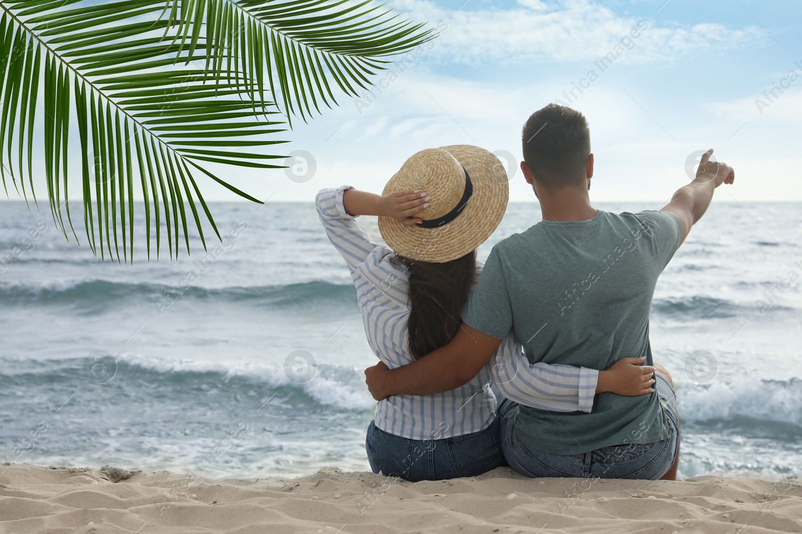 Image of Couple relaxing under palm leaves on tropical beach