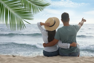 Couple relaxing under palm leaves on tropical beach