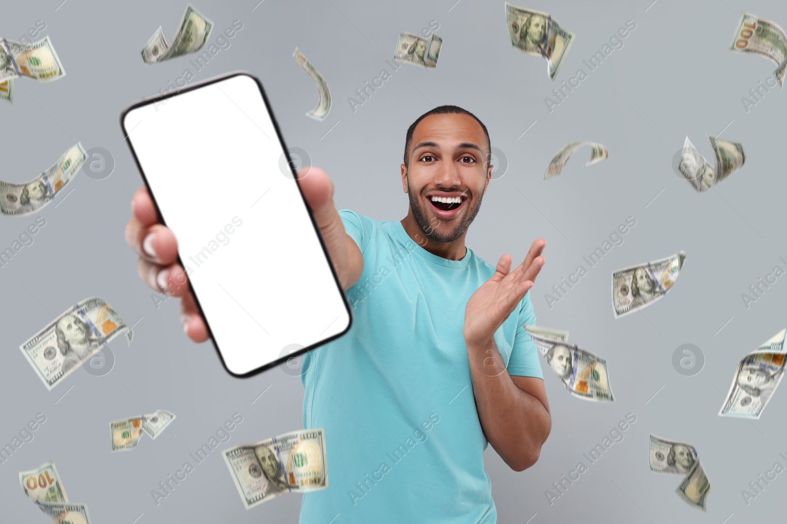 Image of Happy man showing mobile phone with empty screen under money rain on grey background