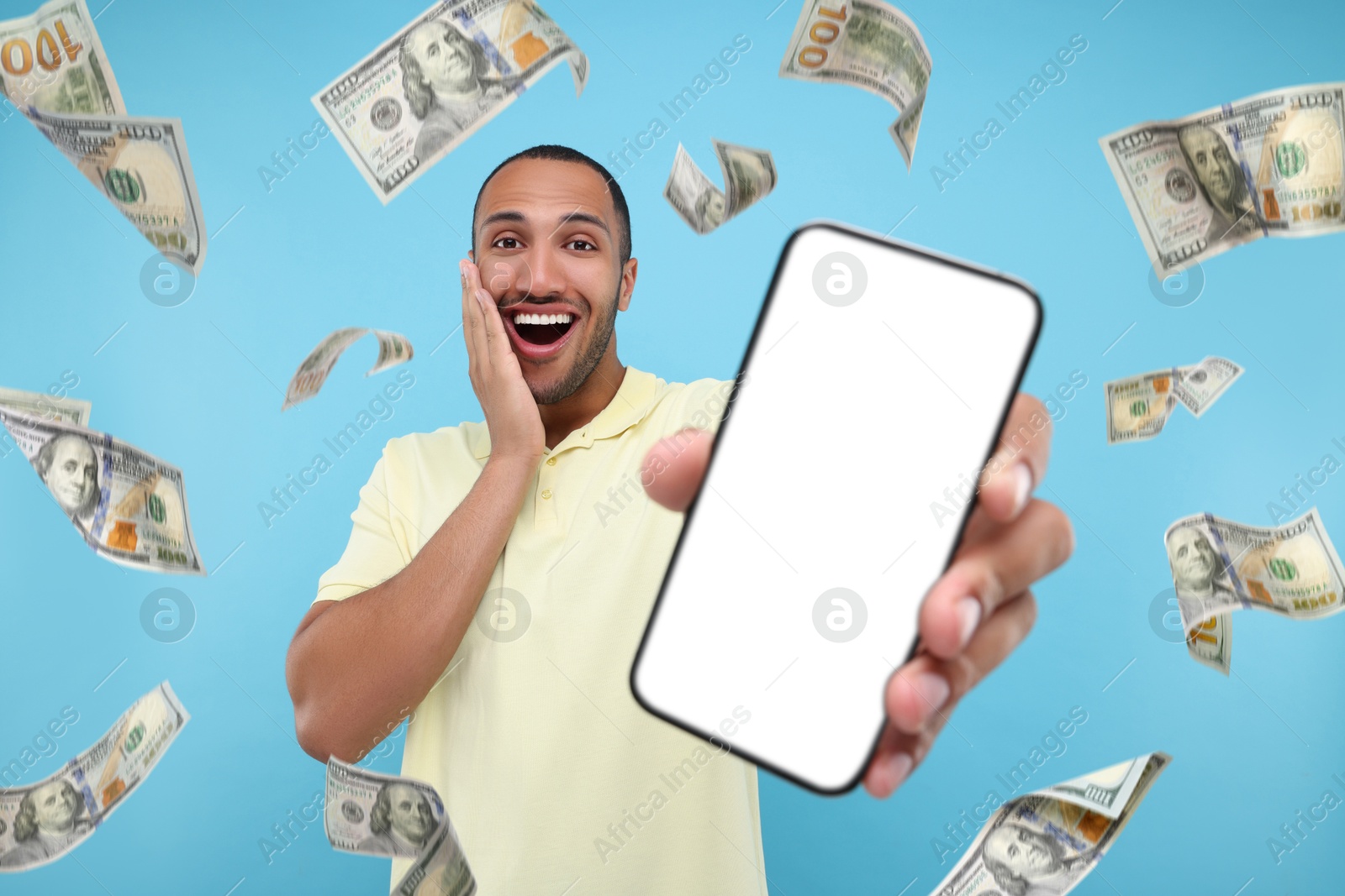 Image of Happy man showing mobile phone with empty screen under money rain on light blue background