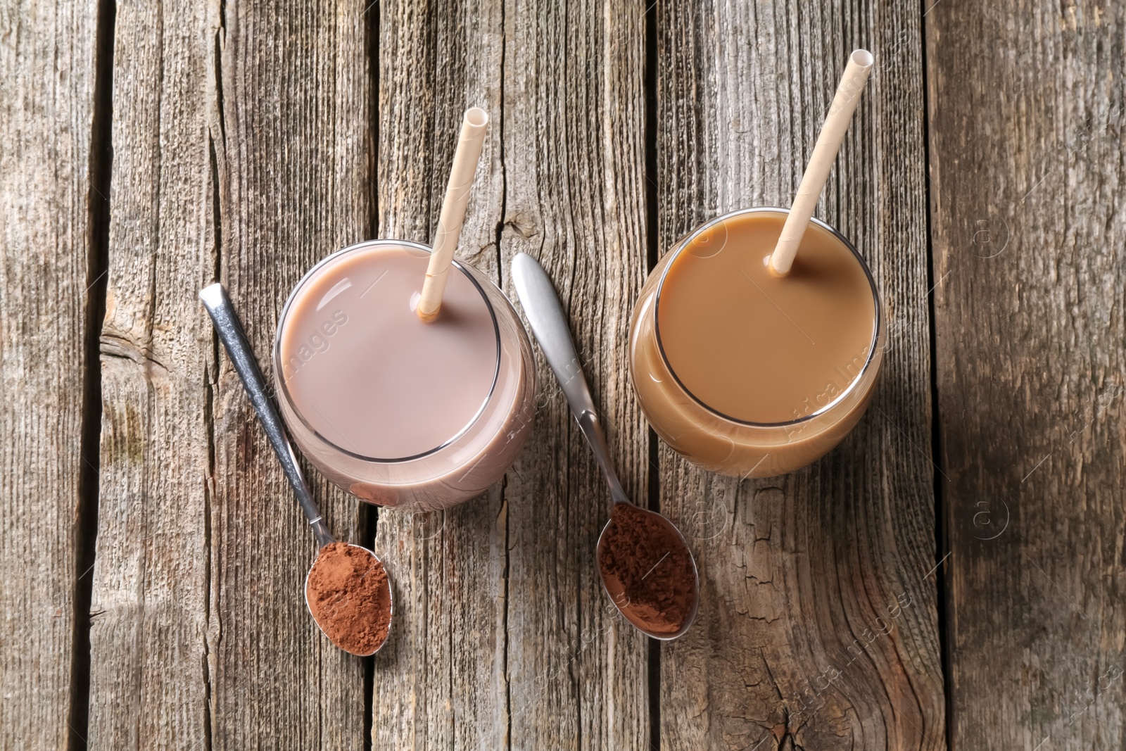 Photo of Delicious protein shakes in glasses and spoons with powder on wooden table, flat lay