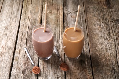 Photo of Delicious protein shakes in glasses and spoons with powder on wooden table