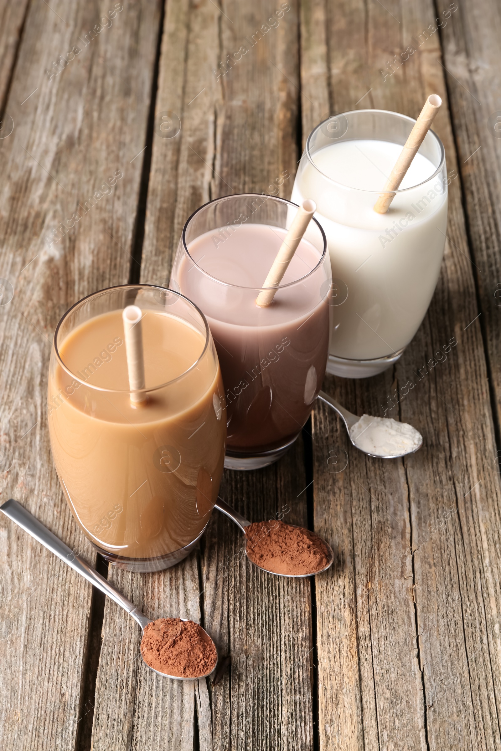 Photo of Delicious protein shakes in glasses and spoons with powder on wooden table