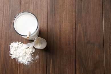 Photo of Delicious protein shake in glass, scoop and powder on wooden table, top view. Space for text