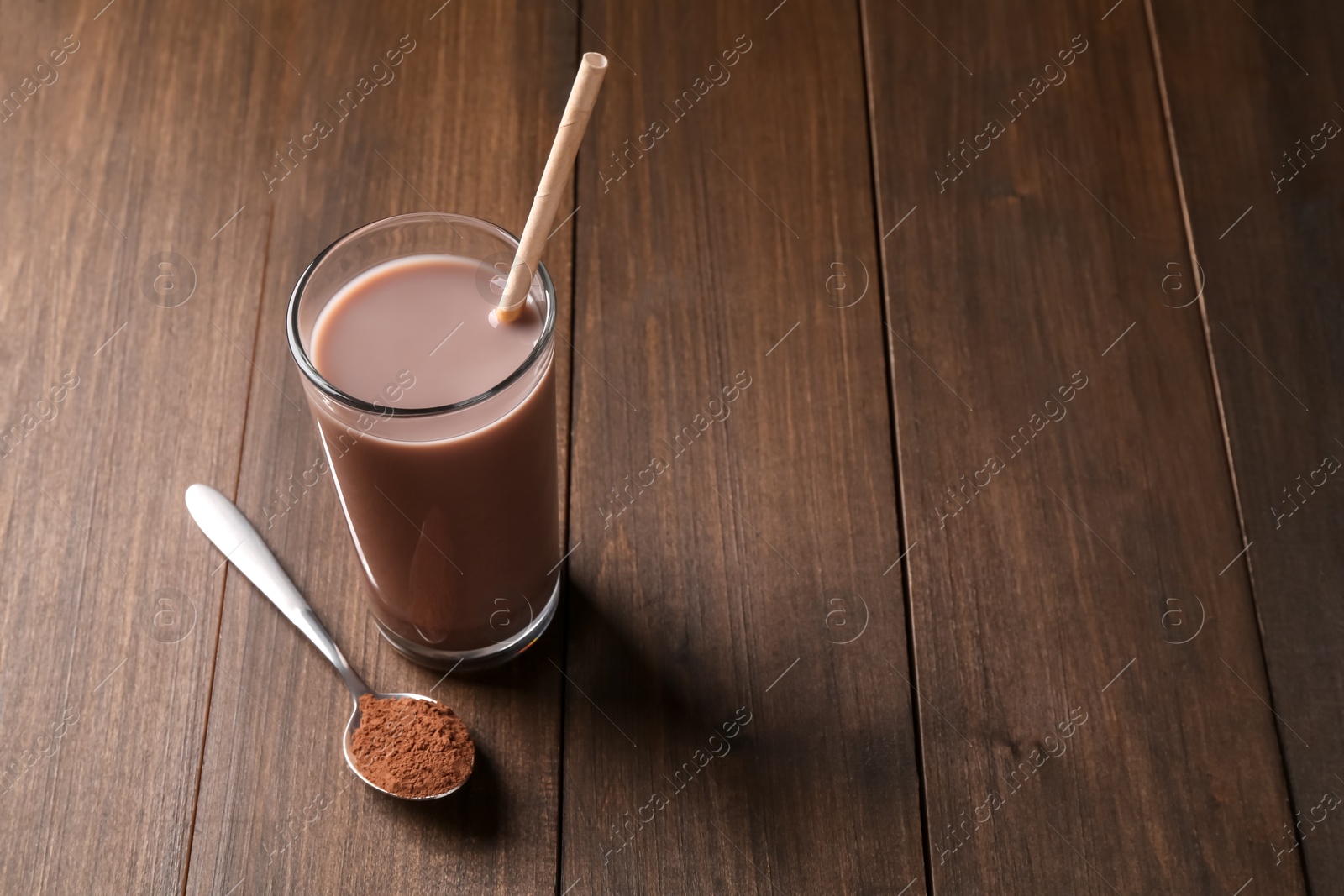 Photo of Delicious protein shake in glass and spoon with powder on wooden table, space for text