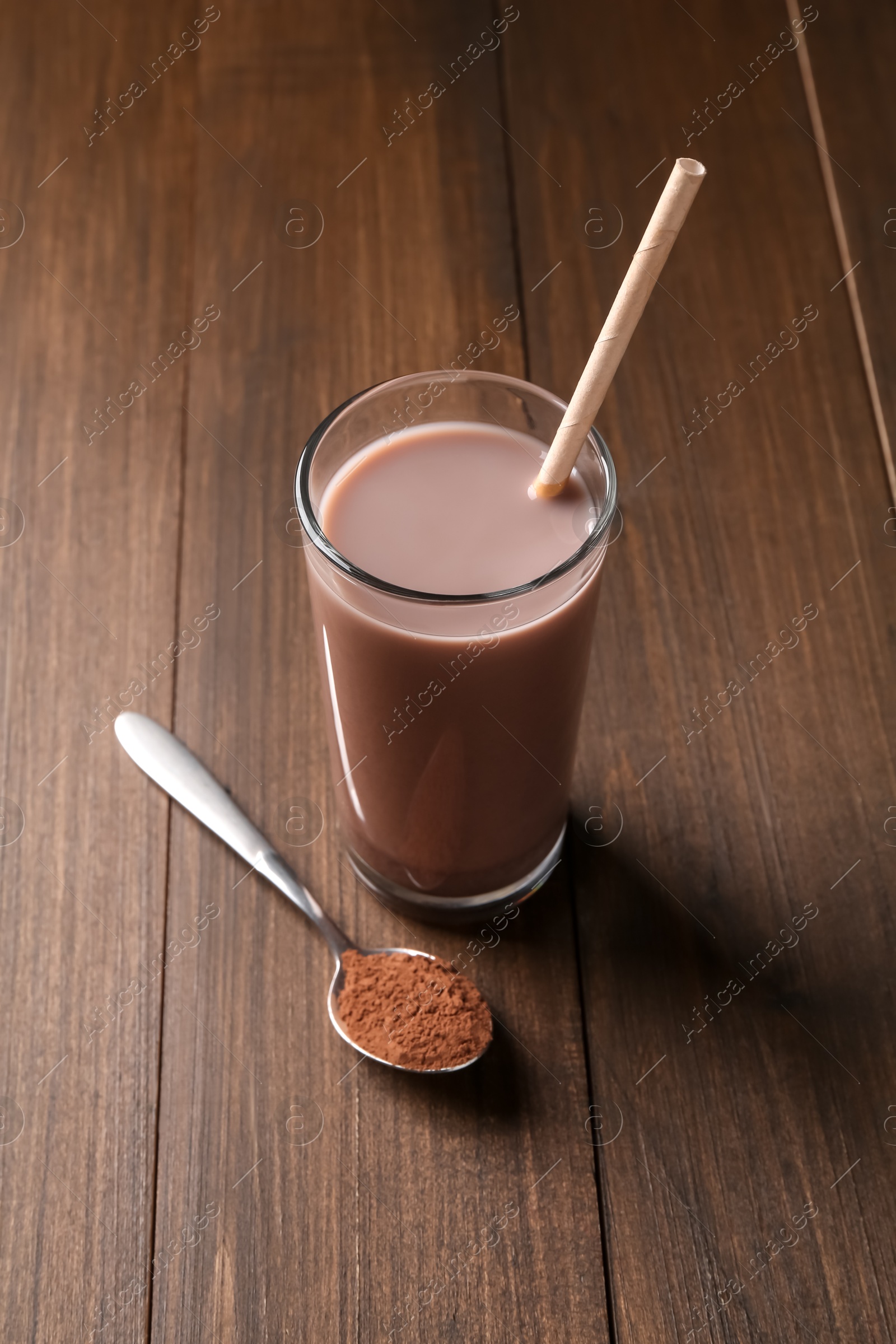 Photo of Delicious protein shake in glass and spoon with powder on wooden table