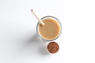 Photo of Delicious protein shake in glass and scoop with powder on white background, top view