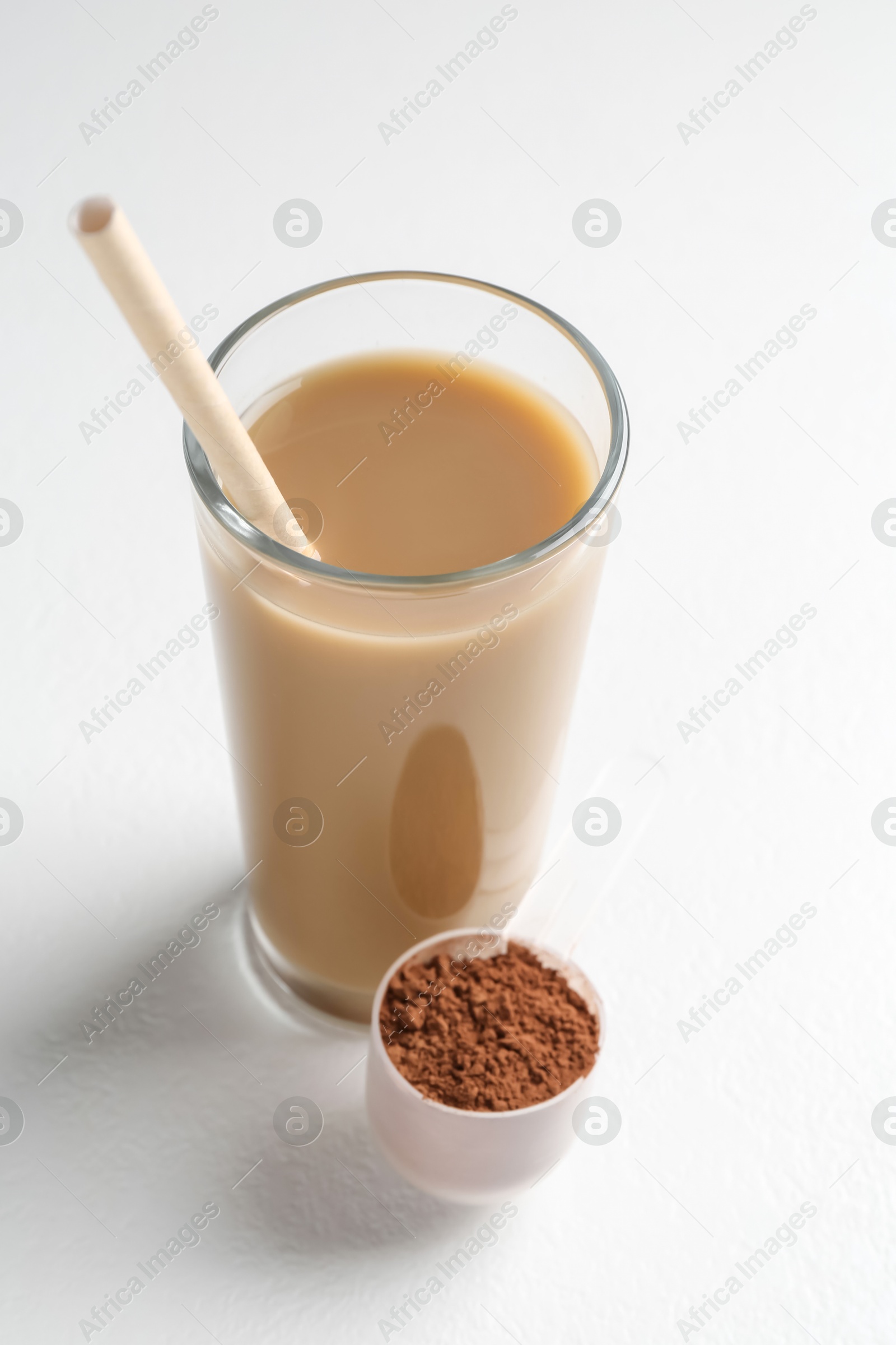 Photo of Delicious protein shake in glass and scoop with powder on white background