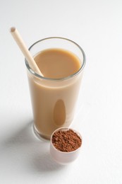 Photo of Delicious protein shake in glass and scoop with powder on white background