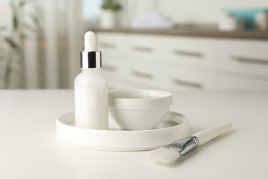 Photo of Peeling procedure. Bottle of chemical peel, bowl with liquid and brush on white table indoors