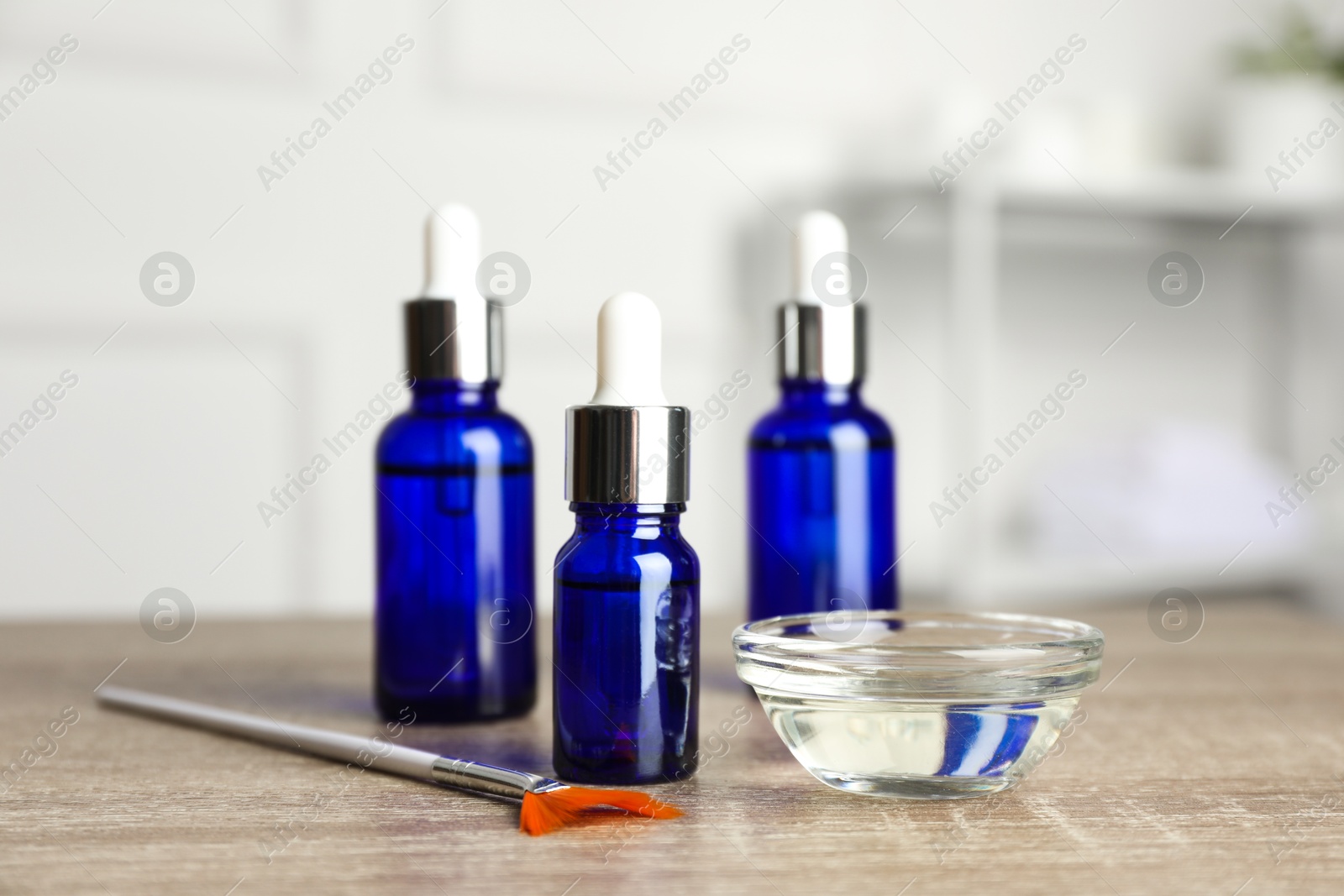 Photo of Peeling procedure. Bottles of chemical peel, bowl with liquid and brush on wooden table indoors