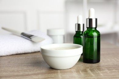 Photo of Peeling procedure. Bottles of chemical peel, bowl with liquid and brush on wooden table indoors. Space for text