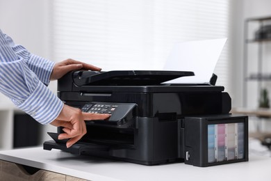 Photo of Woman using modern printer at workplace indoors, closeup