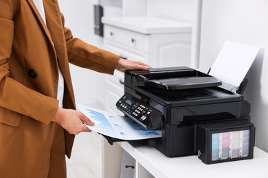 Woman using modern printer at workplace indoors, closeup