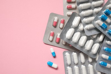 Photo of Antibiotic pills in blisters on pink background, top view. Space for text