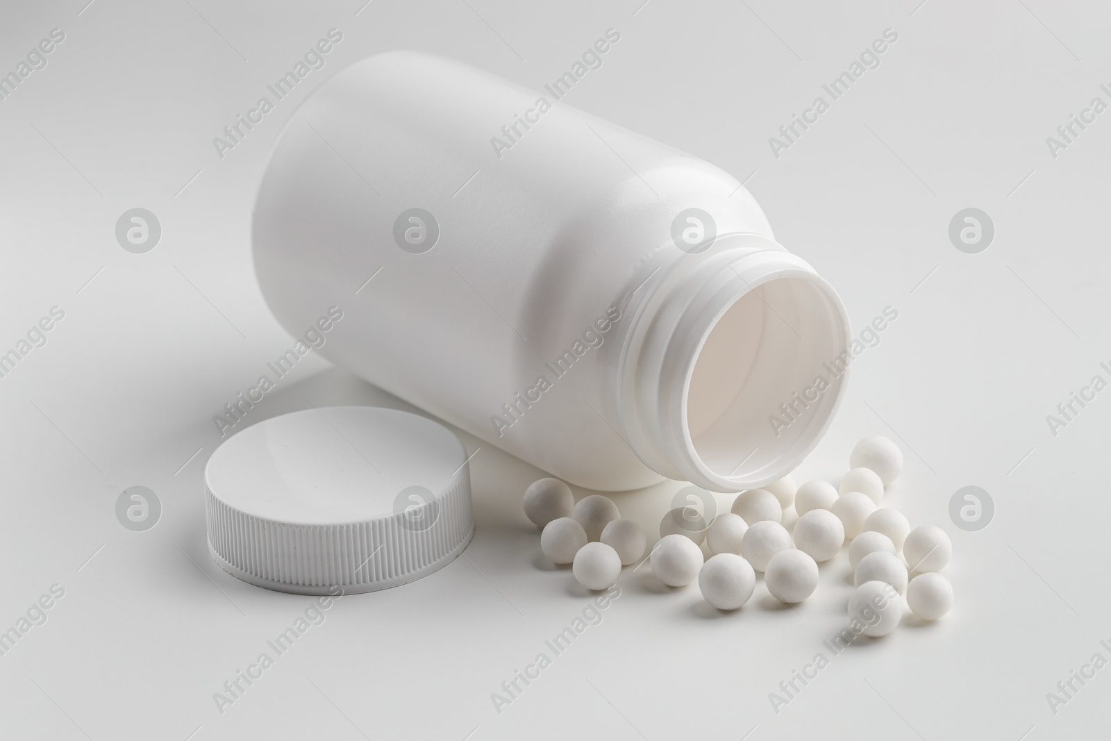 Photo of Homeopathic remedy. Bottle with many pills on white background