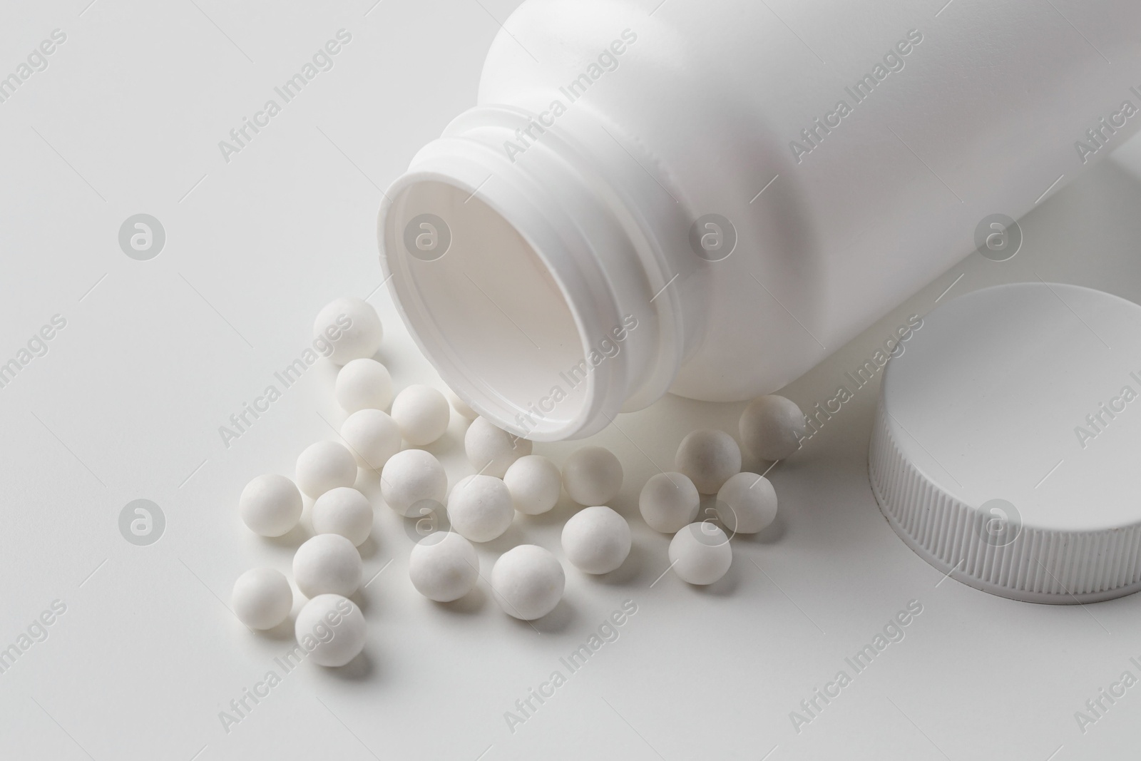 Photo of Homeopathic remedy. Bottle with many pills on white background, closeup