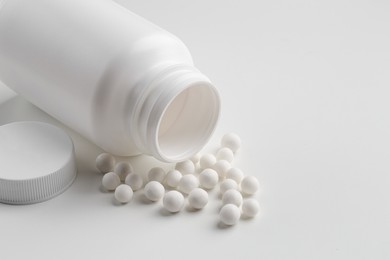 Photo of Homeopathic remedy. Bottle with many pills on white background, closeup. Space for text