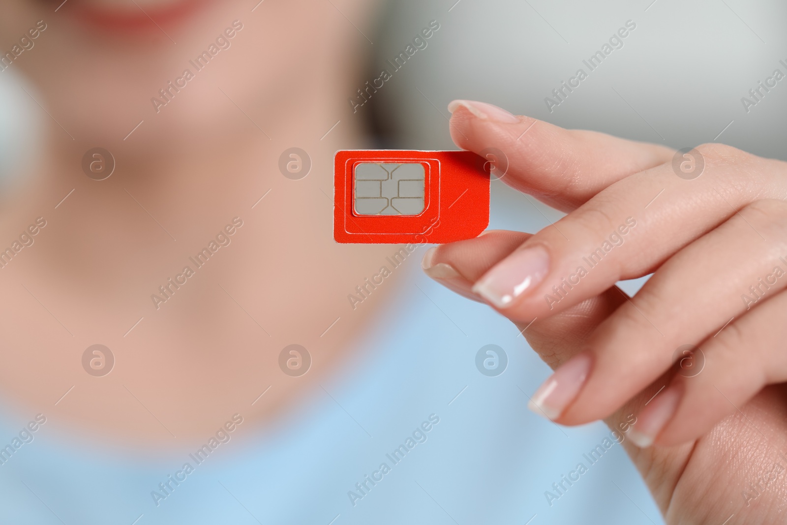 Photo of Woman holding SIM card at home, closeup view