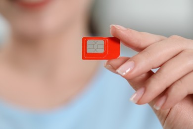 Photo of Woman holding SIM card at home, closeup view