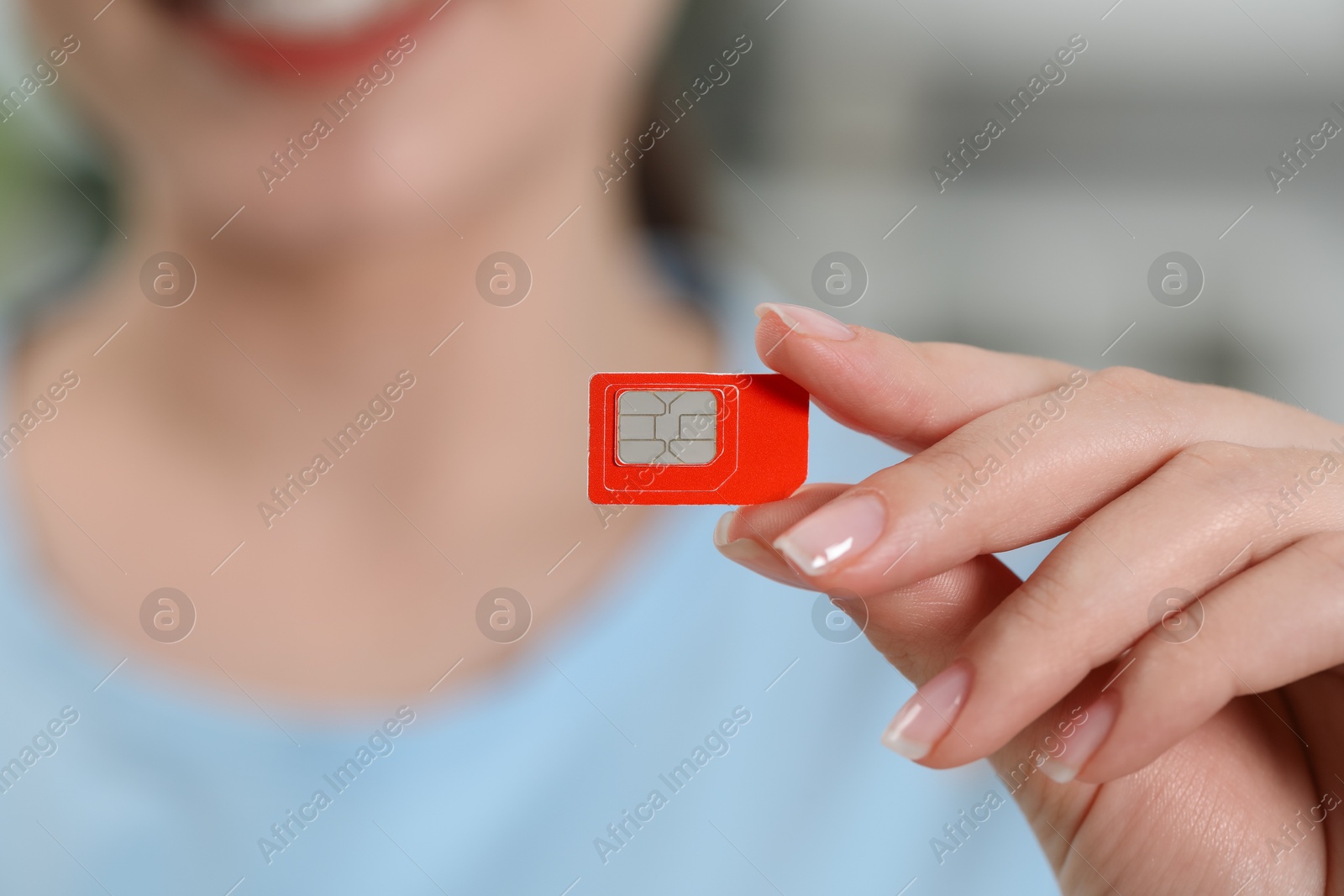 Photo of Woman holding SIM card at home, closeup view