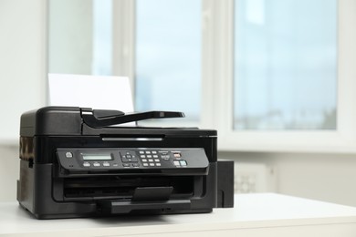 Modern printer with paper on white table in office, space for text