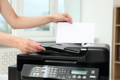 Photo of Woman using modern printer at workplace indoors, closeup