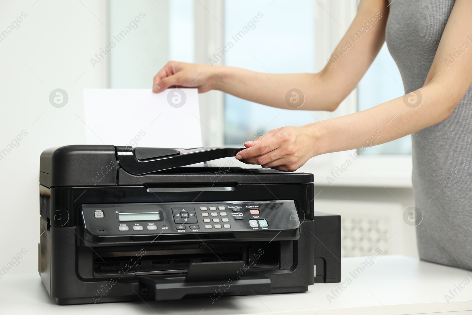 Photo of Woman using modern printer at workplace indoors, closeup