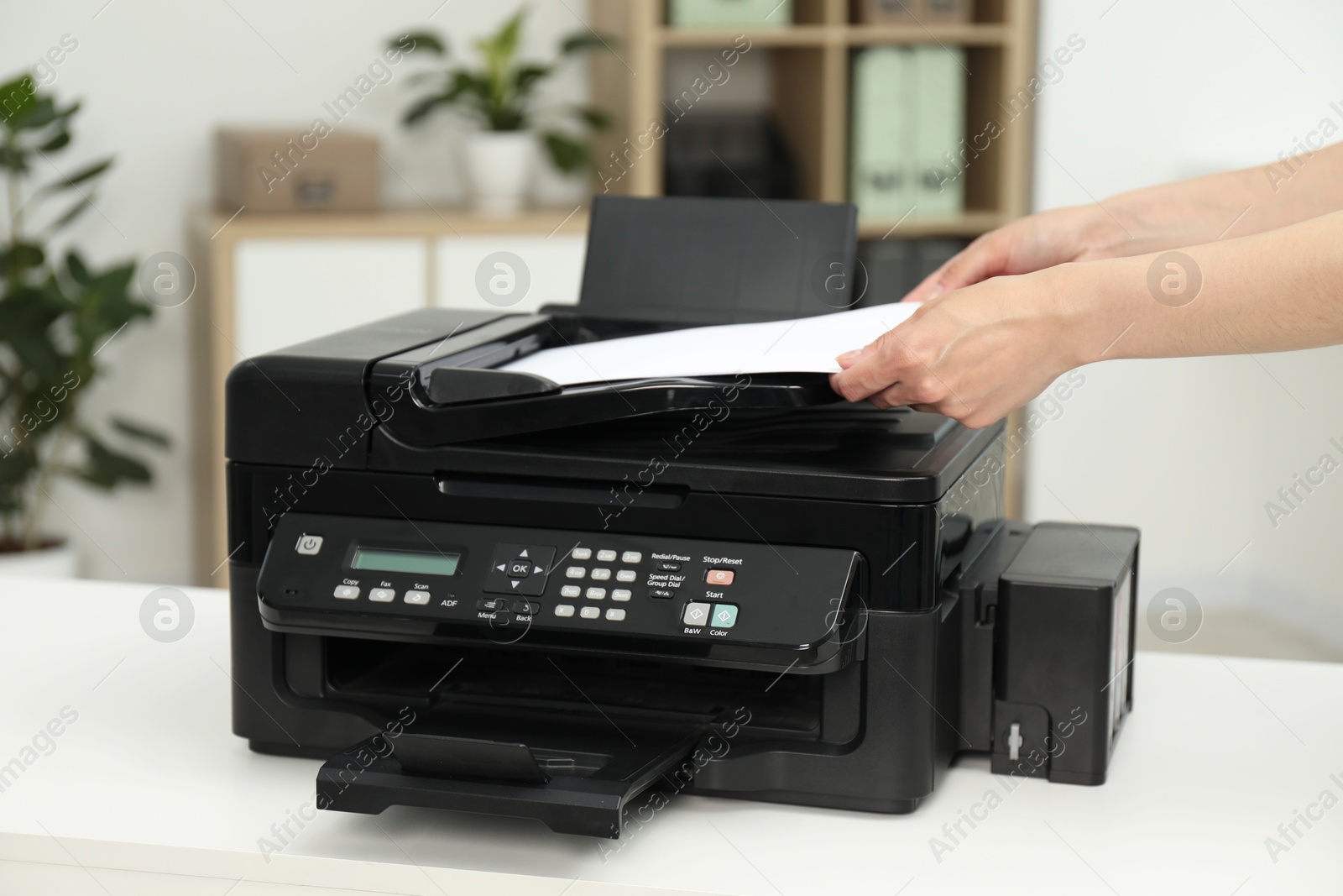 Photo of Woman using modern printer at workplace indoors, closeup