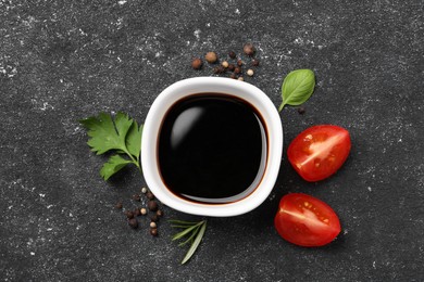 Photo of Balsamic vinegar, tomato and other products on black textured table, flat lay