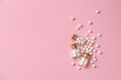 Photo of Homeopathic remedy. Glass bottles and pills on pink background, flat lay. Space for text