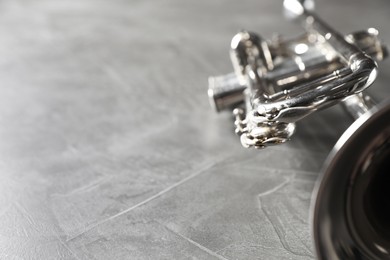 Closeup view of shiny trumpet on grey textured table, space for text. Wind musical instrument