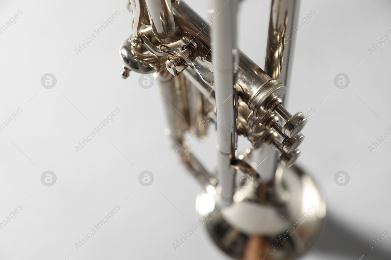 Photo of Closeup view of shiny trumpet on grey background. Wind musical instrument