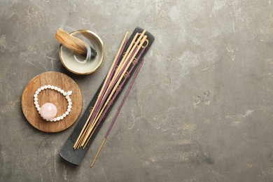 Photo of Incense sticks, holder, Santo Palo and bracelet on gray textured table, flat lay with space for text. Om ligature