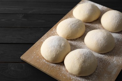 Photo of Raw dough balls on black wooden table