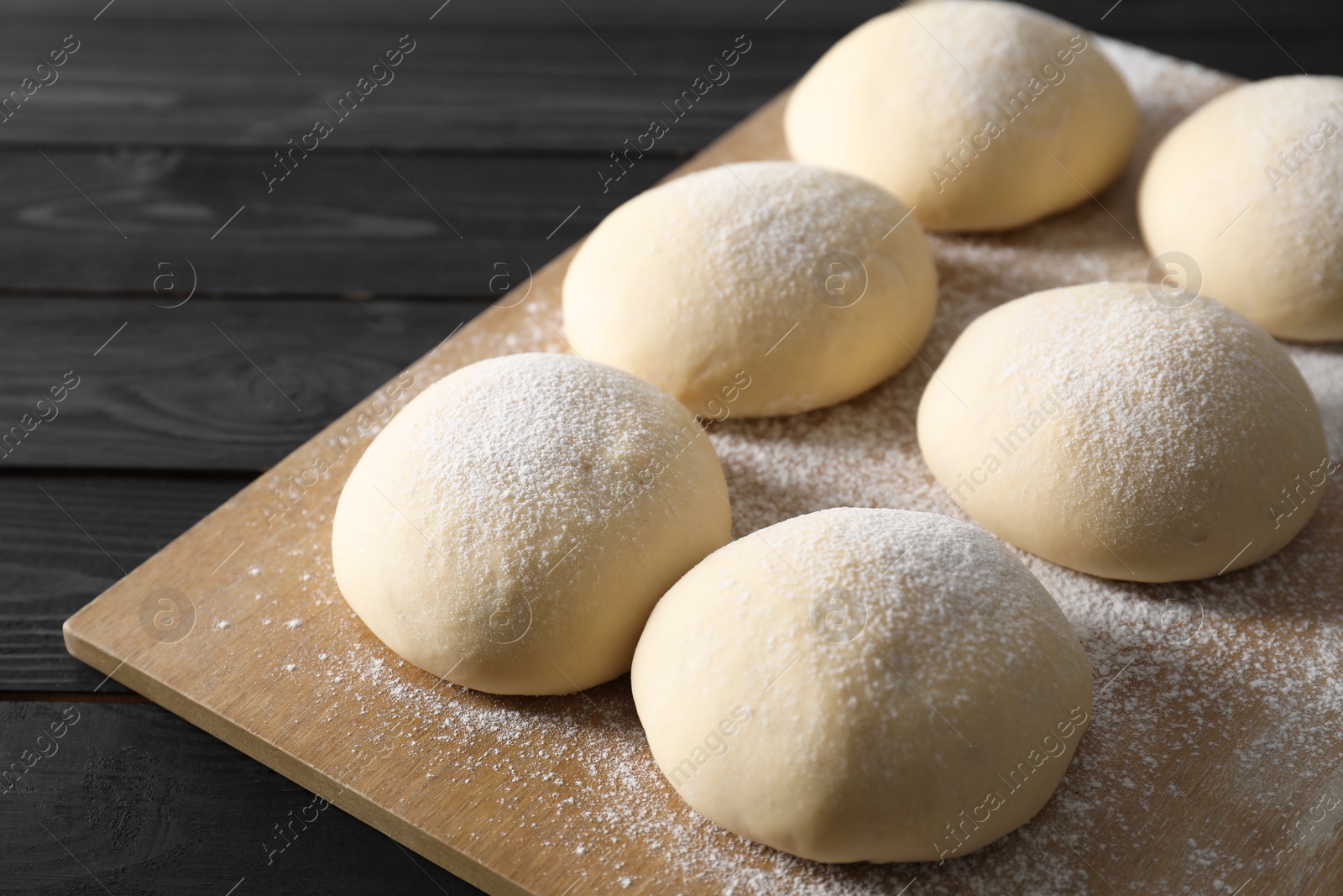 Photo of Raw dough balls on black wooden table