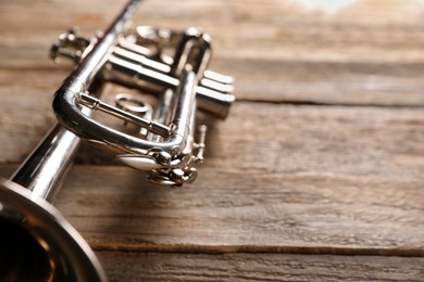 Photo of One trumpet on wooden table, closeup. Space for text